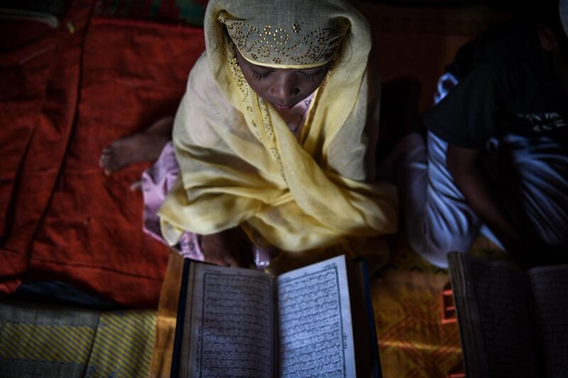 In this photograph taken on August 12, 2018, Saleema Khanam, 8, studies inside a makeshift madrassa (Islamic seminary) with other children in Kutupalong camp, in Ukhia near Cox's Bazar. Islamic seminaries or madrassas, catering to Rohingya children driven from Buddhist-majority Myanmar by a wave of genocidal violence, are springing up in the world's largest refugee camp in Bangladesh since a massive influx of Rohingya Muslims last year. Formal schooling, which suggests a permanent presence, is not allowed in the camps. For many children, the madrassas are the only places to learn. / AFP / CHANDAN KHANNA
