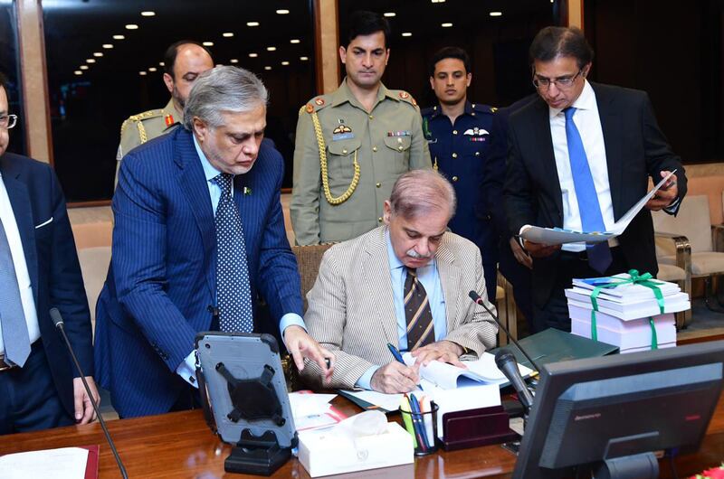 Prime Minister Shehbaz Sharif (centre) signs off on the 2023-24 budget after its approval by the cabinet. EPA