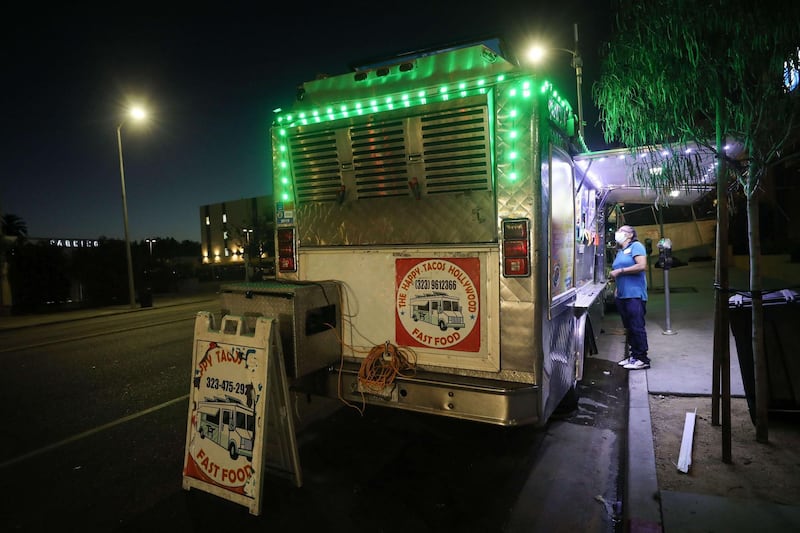 A customer orders from a taco truck in Los Angeles, California. California Governor Gavin Newsom ordered indoor dining restaurants to close again in Los Angeles County and 18 other counties for at least three weeks amid a surge in new coronavirus cases. Restaurants and food trucks may remain open for takeout and drive-through orders. AFP