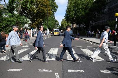 LONDON, ENGLAND - AUGUST 08: Members of the public recreate the iconic album cover for the Beatles album "Abbey Road" on the same pedestrian crossing, fifty years since it was taken, on August 08, 2019 in London, England. The zebra crossing is just outside the recording studios and has become a popular location for music fans visiting London.  (Photo by Leon Neal/Getty Images)