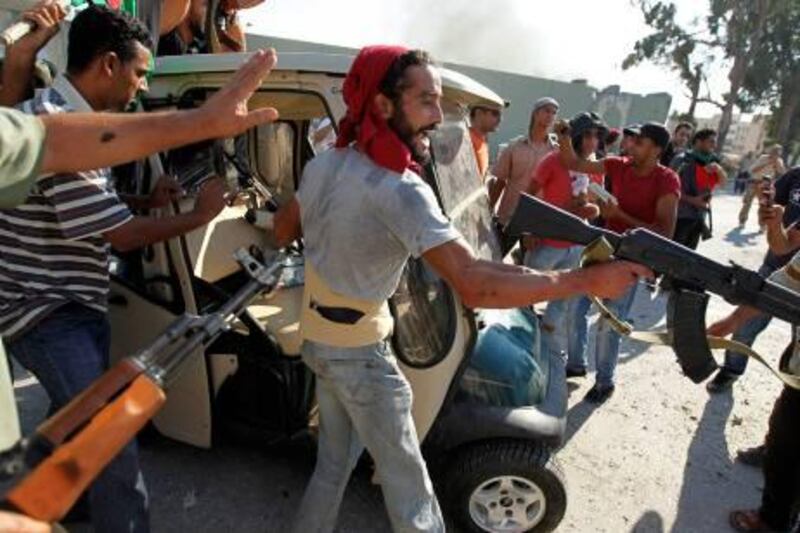 Libyan rebel fighters celebrate near a golf buggy belonging to Muammar Gaddafi at the entrance of Bab al Aziziya compound in Tripoli August 23, 2011. REUTERS/Zohra Bensemra (LIBYA - Tags: POLITICS CIVIL UNREST MILITARY SPORT GOLF CONFLICT) *** Local Caption ***  ZOH05_LIBYA-_0823_11.JPG