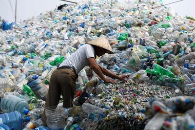 This picture taken on June 4, 2018 shows a man sorting through used plastic bottles at a junkyard in Hanoi. About eight million tonnes of plastic waste are dumped into the world's oceans every year - the equivalent of one garbage truck of plastic being tipped into the sea every minute... of every day. Over half comes from five Asian countries: China, Indonesia, the Philippines, Thailand and Vietnam, according to a 2015 study in Science journal. / AFP / Nhac NGUYEN
