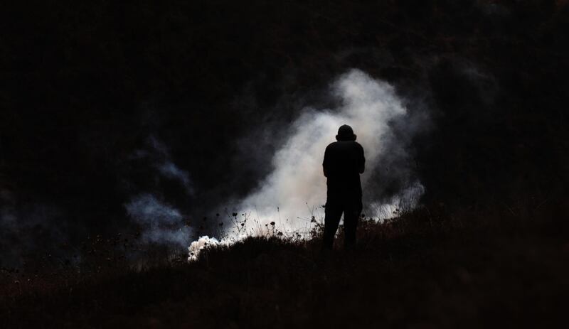 A Palestinian protester seeks cover from a tear gas grenade during clashes after a demonstration against Israel's settlements in the village of Asera near the northern West Bank city of Nablus. EPA