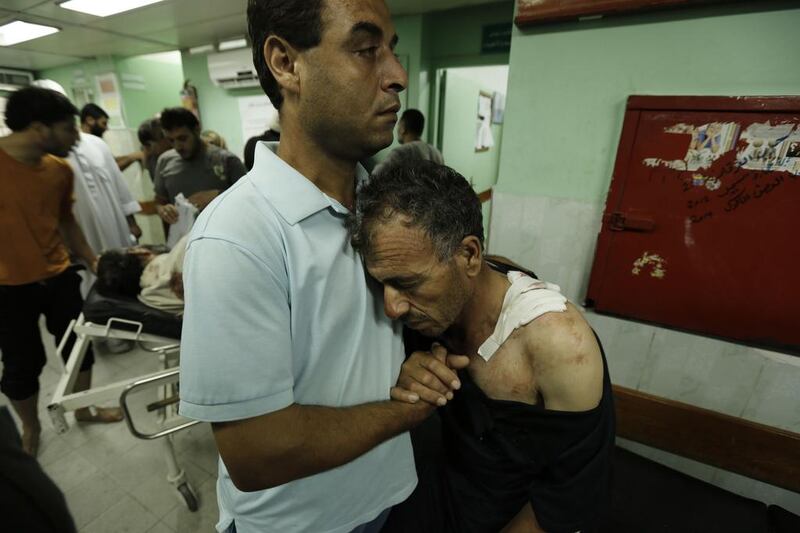 A Palestinian man hugs his father who was wounded in the attack. Mohammed Abed / AFP Photo 