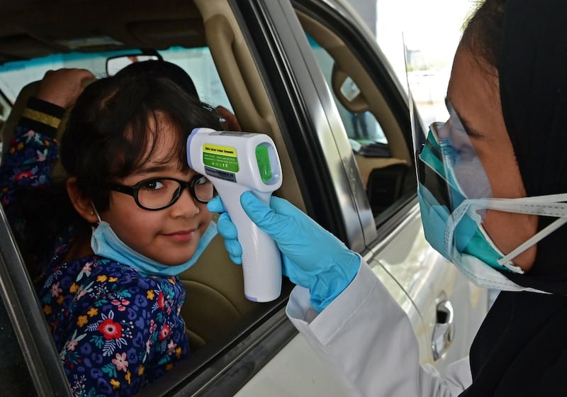 A nurse measures the body temperature of a small girl.