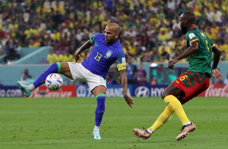 Brazil's Dani Alves in action with Cameroon's Nicolas Moumi Ngamaleu. Reuters