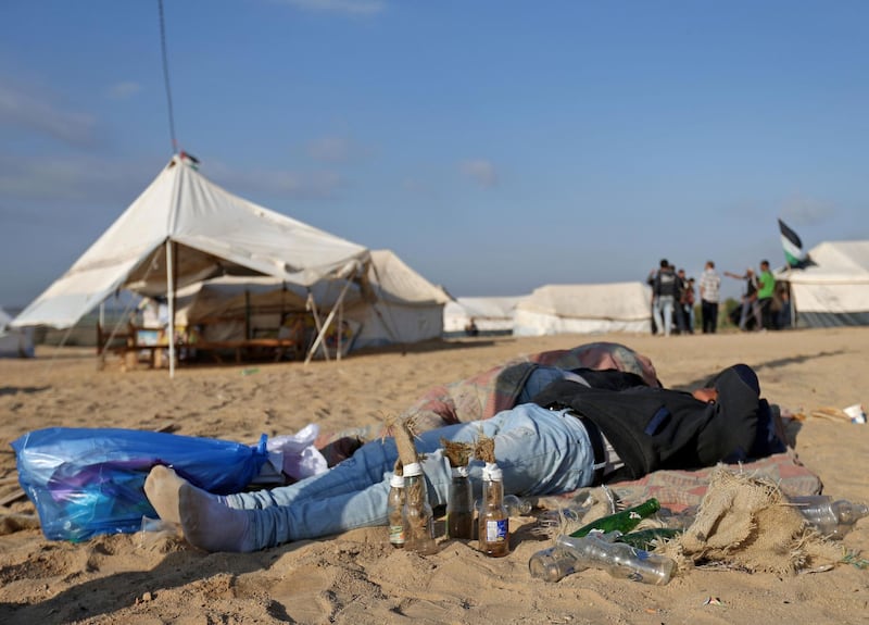 A man rests on the sand next to bottles to be used as molotov cocktails as Palestinians prepare to demonstrate along the border with the Gaza strip, east of Jabalia. Mohammed Abed / AFP