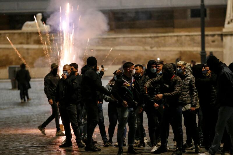 Flares explode as people gather in Piazza del Popolo square during a protest by the Forza Nuova far-right group against coronavirus restrictions, in Rome, Italy. AP