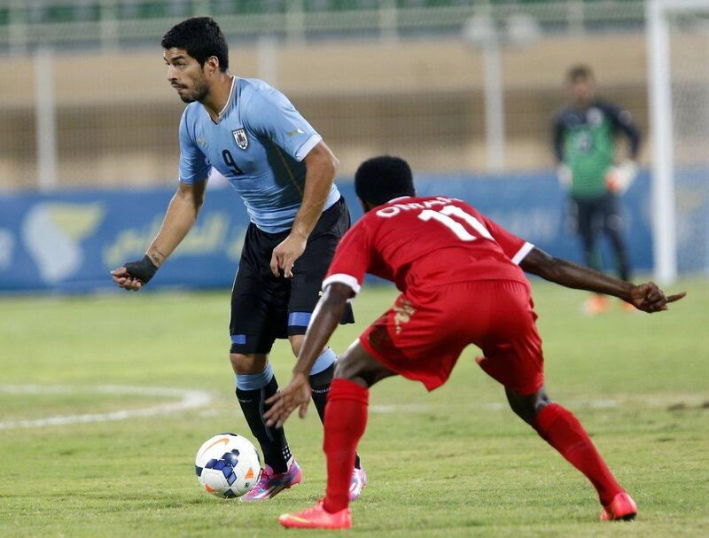 Luis Suarez dribbles with the ball against Oman's Saad Al Mukhaini on Monday during an international friendly in Al Buraimi, Oman. Mohammed Mahjoub / AFP / October 13, 2014