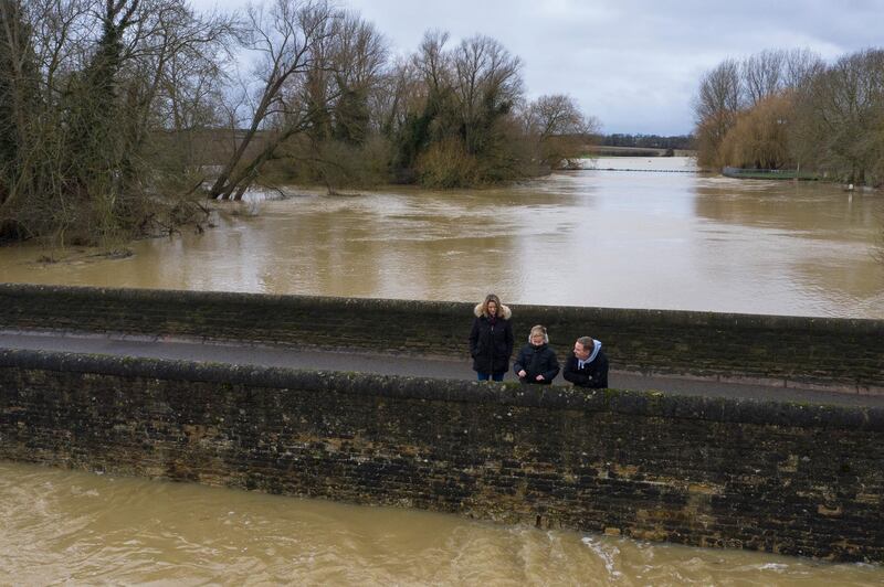 A family look at high water from a bridge looking over the River Great Ouse in Pavenham, England. Getty Images