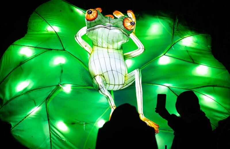 People take photographs of an illuminated lantern at the Lightopia Christmas festival, in Manchester. The display is open to the public from November 24, 2022 to January 2, 2023. EPA