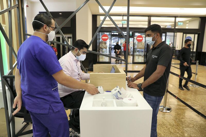 DUBAI, UNITED ARAB EMIRATES , October 14 – 2020 :- Anto Antony (right) taking the token for his COVID-19 nasal swab test at the COVID 19 testing station set up at Mall of the Emirates in Dubai. (Pawan Singh / The National) For News/Online. Story by Sarwat
