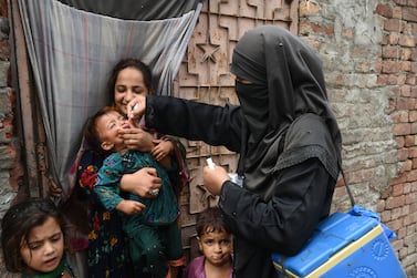 A health worker administers polio vaccine drops to a child during a polio vaccination campaign at a slum area in Lahore on August 2, 2021. (Photo by Arif ALI / AFP)
