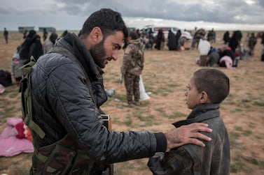 A 12-year-old orphan called Mohamed speaks with a fighter from the Syrian Democratic Forces after leaving Baghouz, the last ISIS-held territory in Syria. Campbell MacDiarmid for The National