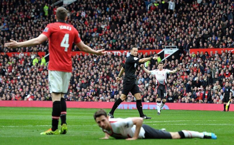 Referee Mark Clattenburg, centre, points to the penalty spot for the second time after Manchester United defender Phil Jones, left, fouled Liverpool midfielder Joe Allen. Paul Ellis / AFP / Mach 16, 2014