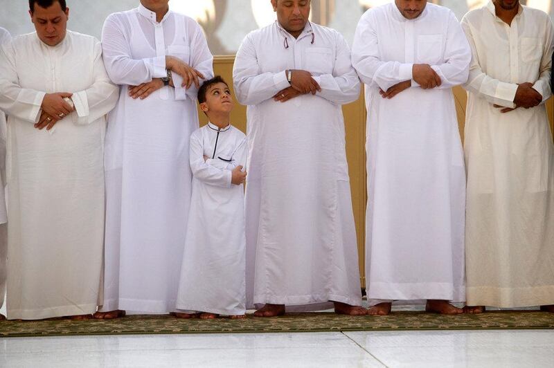 A boy looks up to a relative during Eid prayers at Sheikh Zayed Grand Mosque. Christopher Pike / The National