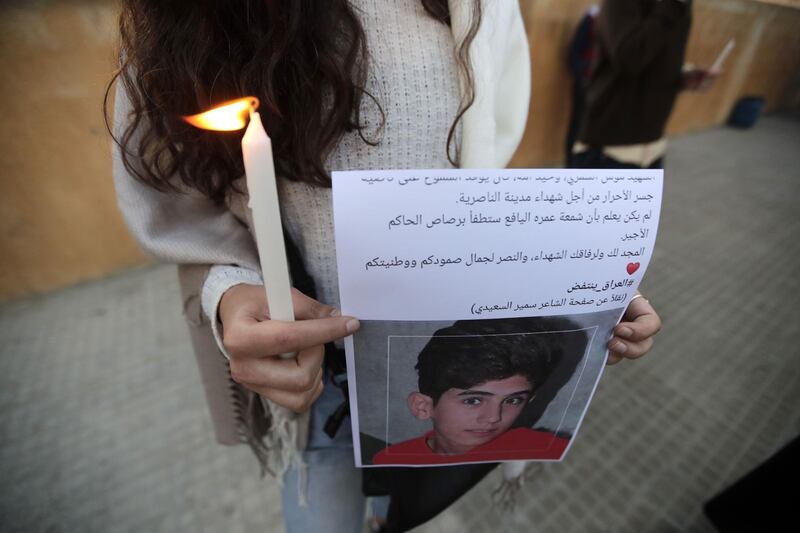 A Lebanese demonstrator holds a picture showing a young Iraqi killed during protests, as she takes part in a candlelight vigil staged outside Iraq's embassy to denounce the excessive use of force against demonstrators there, in the capital Beirut. AFP