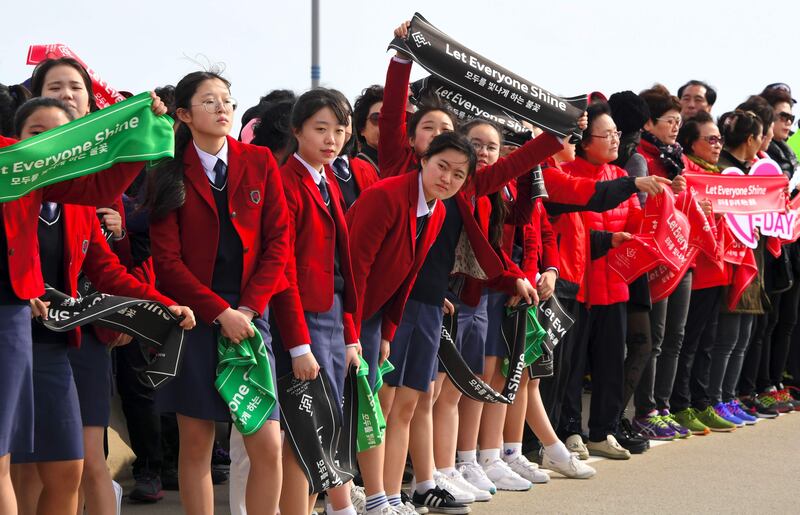 People wave banners reading "Let Everyone Shine," during a ceremony of the start the Olympic torch relay across South Korea at Incheon bridge, west of Seoul, on November 1, 2017. Jung Yeon-Je / AFP