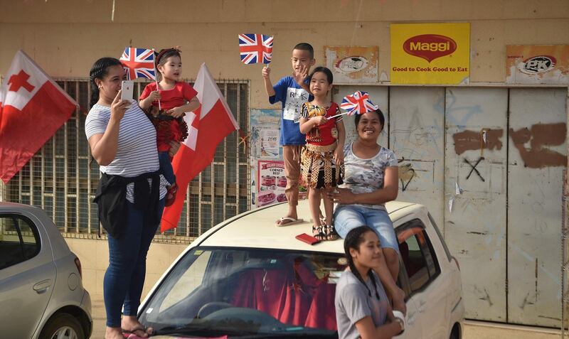 People cheer for Britain's Prince Harry and his wife Meghan, Duchess of Sussex as their convoy from Fua'amotu airport in Tonga passes by. Prince Harry and his pregnant wife Meghan left Fiji after a three-day official visit and arrived in Tonga as part of their tour of Australia and the South Pacific.  AFP