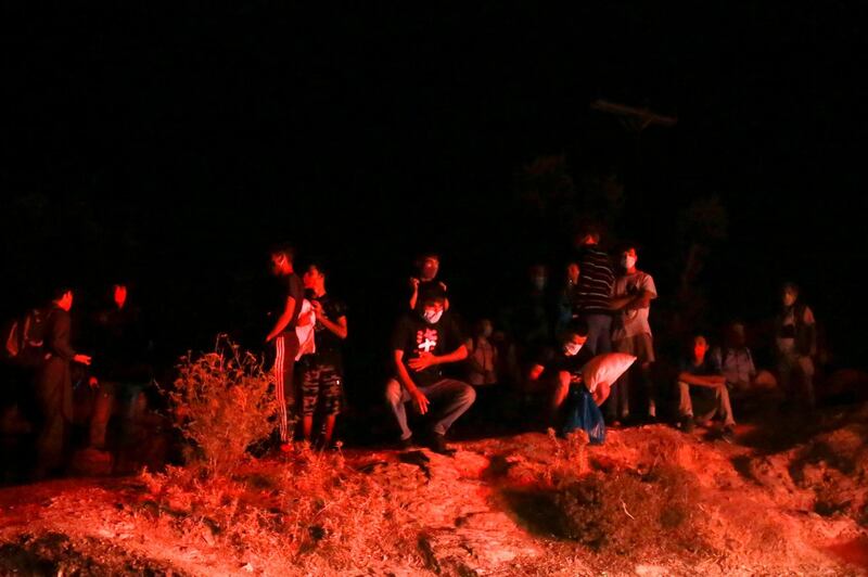 Refugees wearing facemasks gather outside the Moria camp on the island of Lesbos during a major fire there.   AFP