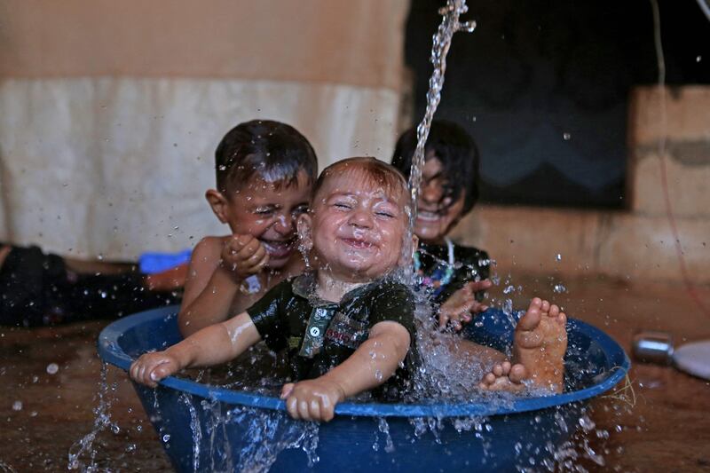 Children play in a makeshift pool in the back of a pick-up truck as the temperature soars, at a camp for the internally displaced in Idlib, north-western Syria. All photos: AFP