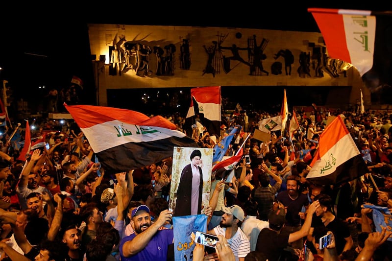 Followers of Shiite cleric Muqtada al-Sadr, displayed on the poster, celebrate in Tahrir Square, Baghdad, Iraq, early Monday, May 14, 2018. The political coalition of influential Shiite cleric Muqtada al-Sadr took an early lead in Iraq's national elections in partial returns announced late Sunday by the Iraqi electoral commission. (AP Photo/Karim Kadim)