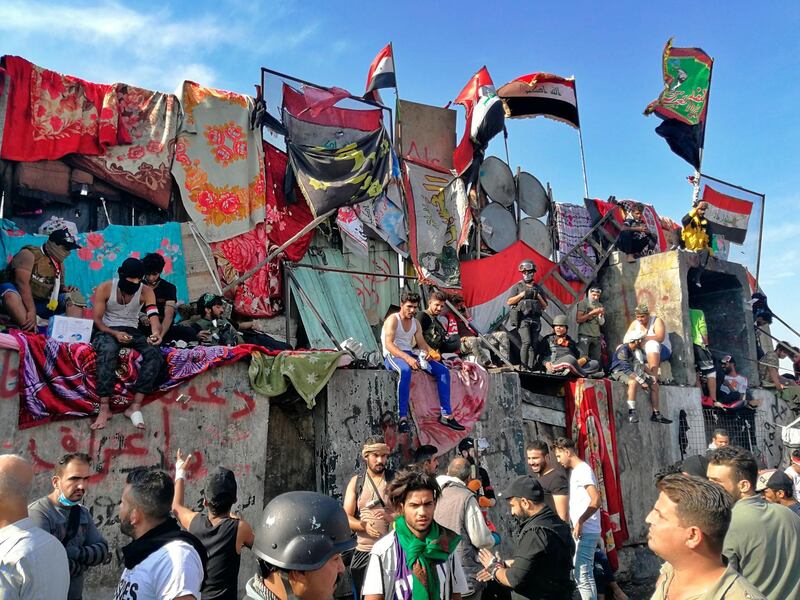 Anti-government protesters stand on barriers set up by security forces to close a bridge leading to the Green Zone government areas during ongoing protests in Baghdad, Iraq. AP Photo