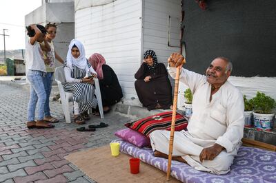 Members of a Syrian refugee family sit outside their home at the Boynuyogun refugee camp in Hatay, Turkey. Getty Images