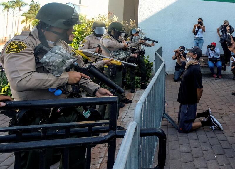 A demonstrator knees as Los Angeles County sheriff's deputies prepare to fire pepper balls, flash-bangs and rubber bullets in a protest against the death of 18-year-old Andres Guardado and racial injustice, in Compton, California, U.S. REUTERS