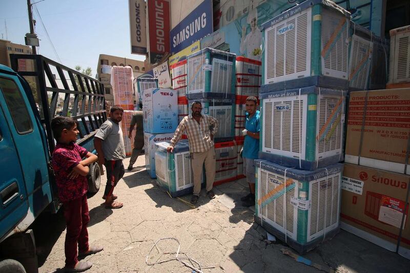 Iraqi men stand next a/c units in Baghdad. Haider Mohammed Ali / AFP Photo