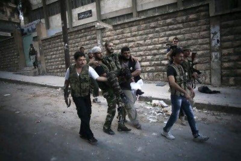 Free Syrian Army fighters carry a wounded comrade in the Izaa district in Aleppo, Syria. As fresh bloodshed grips the north of the country, peace envoy Lakhdar Brahimi is to meet with Bashar Al Assad.