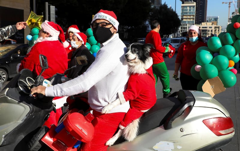 A man wearing a protective face mask rides a motorbike with a dog dressed up as Santa Claus, during a parade ahead of Christmas in downtown Beirut, Lebanon. Reuters
