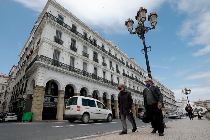 Men wearing face masks walk in Algiers. AP Photo