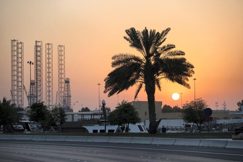 Abu Dhabi, United Arab Emirates, August 14, 2017:    The sun sets behind a palm tree along the Corniche across from Mina Zayed in Abu Dhabi on August 14, 2017.  Abu Dhabi municipality recently launched the Green Abu Dhabi initiative, a wide ranging campaign to care for and protect trees and green spaces throughout the city. Christopher Pike / The National

Reporter: Mina Aldroubi
Section: News