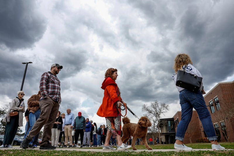 A woman with a dog stands in line to cast her vote in the South Carolina Republican presidential primary election, at the Jennie Moore Elementary School, in Mount Pleasant, US. Reuters