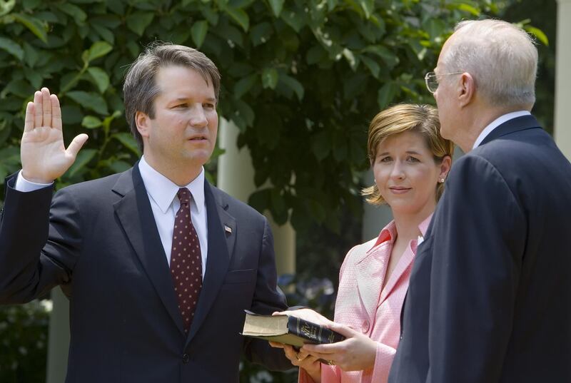 (FILES) In this file photo taken on June 01, 2006 Brett Kavanaugh (L) is sworn in as a US Court of Appeals Judge for the District of Columbia by US Supreme Court Justice Anthony Kennedy (R) as Kavanaugh's wife Ashley (C) holds the Bible during ceremonies 01 June 2006 in the Rose Garden of the White House in Washington, DC.  President Donald Trump will announce his US Supreme Court pick Monday July 9, an intensely anticipated decision likely to swing the bench rightward for years to come and which has Washington readying for an explosive confirmation battle. / AFP / Paul J. RICHARDS
