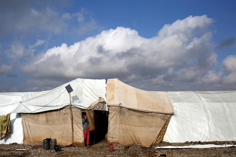An Iraqi girl looks out from her tent after heavy rainfall caused flooding in Salamiya Camp, southeast of Mosul. EPA