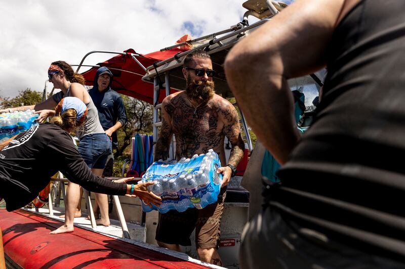Volunteers load supplies on to a boat bound for West Maui at the Kihei boat landing. AP