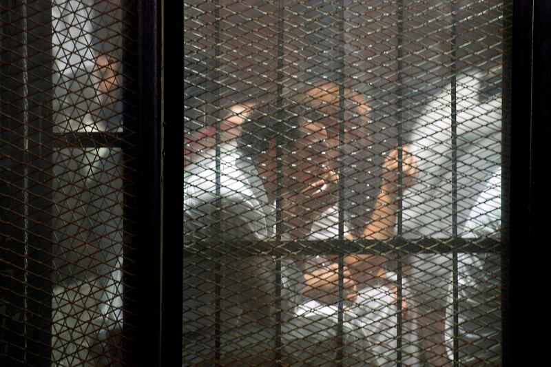 This picture shows detainees inside the soundproof glass dock of the courtroom during the trial of 700 defendants including Egyptian photojournalist Mahmoud Abu Zeid, widely known as Shawkan, in the capital Cairo, on September 8, 2018. - An Egyptian court on September 8 handed a five-year jail sentence to prominent photojournalist Zeid, known as Shawkan, who earlier this year received UNESCO's World Freedom Prize. Shawkan was one of more than 700 defendants on trial in the same case, most of them facing charges of killing police and vandalising property during the clashes. The same court that jailed him also confirmed on Saturday death sentences initially issued in July against 75 defendants, including leaders of Morsi's outlawed Muslim Brotherhood. (Photo by Mohamed el-Shahed / AFP)