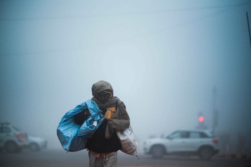TOPSHOT - A man crosses a street under heavy foggy conditions in New Delhi on December 30, 2019. / AFP / Jewel SAMAD
