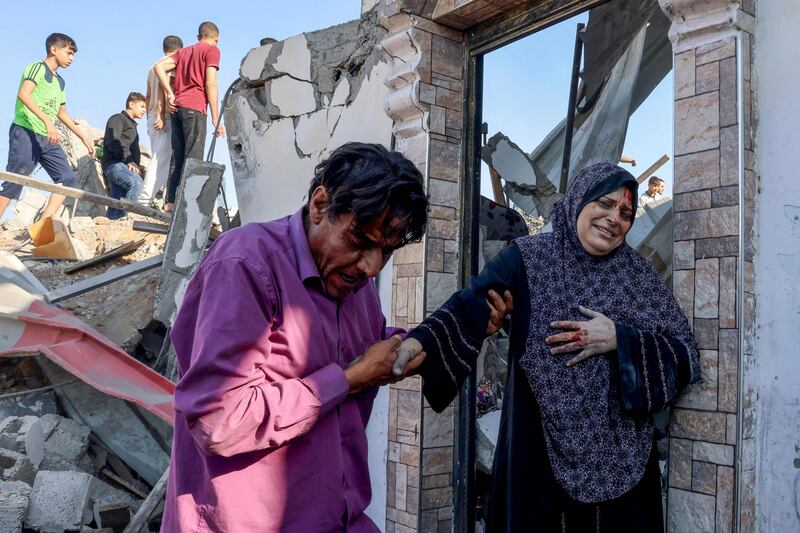Palestinians look for survivors in the rubble of a destroyed building hit during an Israeli air strike, as an injured woman is helped in Rafah in the southern Gaza Strip, on October 13. AFP