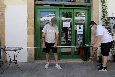 epa09188968 People measure the distance between tables at a cafe as businesses reopen in Nicosia, Cyprus, 10 May 2021. The local government is enforcing a compulsory display of proof of vaccination, negative Covid-19 test carried out within the last 72 hours, or convalescence from the disease in the past six months, in areas where people gather in numbers, such as restaurants, taverns, shopping malls, gyms, theatres, places of worship and churches.  EPA/KATIA CHRISTODOULOU