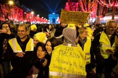 epa07255868 A 'Yellow Vests' protester wear a vest reading 'Go Macron, President of the Rich, Bleeder of the Poor' as a large crowd gather on the Champs Elysees to view a lights show and firework during the celebrations of the New Years Eve 2019 in Paris, France, 31 December 2018.  EPA/IAN LANGSDON