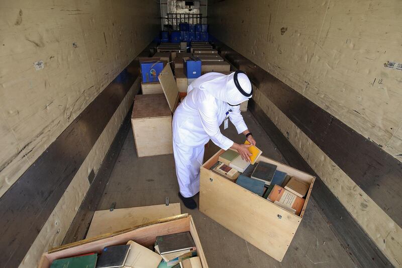 Employee at the Kuwaiti Information Ministry Essam al-Said inspects boxes in the back of a truck containing Kuwaiti archives seized during the Iraqi invasion of the Gulf emirate in 1990, after their restitution by Iraqi authorities in Kuwait City, on March 28, 2021. / AFP / YASSER AL-ZAYYAT
