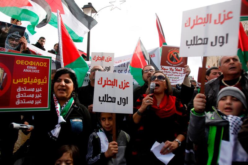 Palestinian protesters hold placards as the convoy of Jerusalem's Greek Orthodox patriarch Theophilos III arrives in the West Bank town of Bethlehem on January 6, 2018 ahead of a Christmas service according to the Eastern Orthodox calendar. 
The municipalities of Bethlehem, Beit Sahour and Beit Jala, all in the Israeli-occupied West Bank, called for the boycott over Jerusalem's Greek Orthodox patriarch allegedly allowing controversial real estate sales.  / AFP PHOTO / Musa AL SHAER