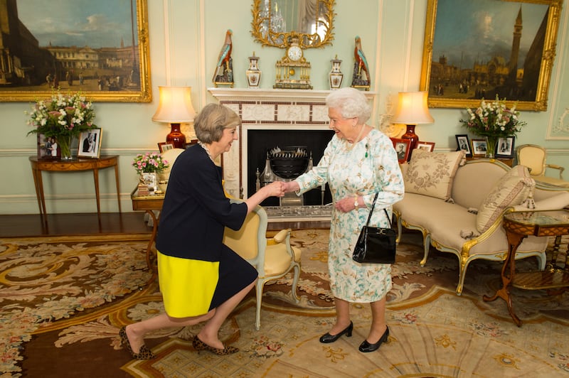 The then new leader of the UK Conservative Party, Theresa May, kneels as she is greeted by Queen Elizabeth II, in Buckingham Palace in London, on July 13, 2016. AFP