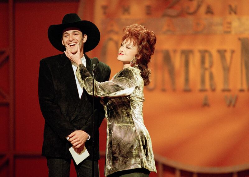 In this May 3, 1994, photo, Naomi Judd pinches the cheeks of Luke Perry after asking him about the title of his new movie, "8 Seconds," during the 29th Academy of Country Music Awards in Universal City, Calif. Photo: AP