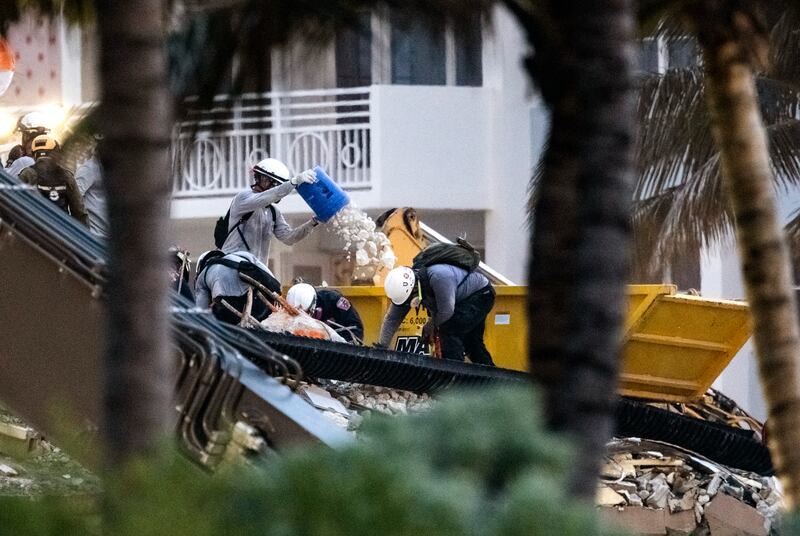 A search and rescue worker tips rubble into a skip. Miami Herald via AP