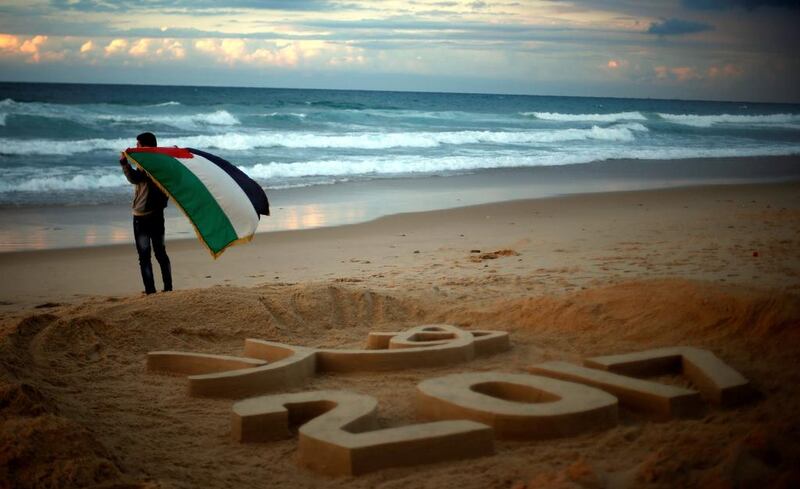 Palestine artist Yazed Abu Jarad holds a Palestine flag after making a sand sculpture that reads “Welcome 2017” at a beach in the northern Gaza Strip on December 31, 2016. Suhaib Salem / Reuters
