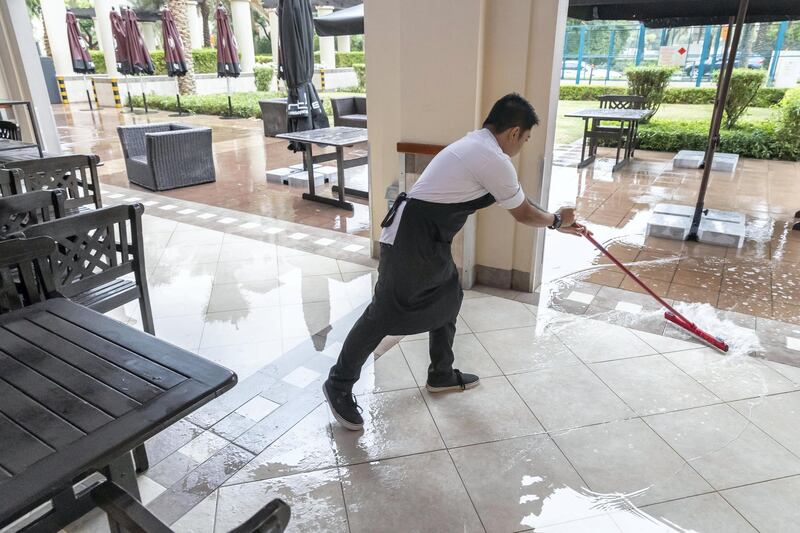 DUBAI, UNITED ARAB EMIRATES. 10 JANUARY 2020. Heavy rains in Dubai during the night had residenst wake up to wet pavements and large water puddles with some areas experiencng mild flooding. A waiter at Burts in The Greens sweeps away some water from the nights rains to get ready for the business day. (Photo: Antonie Robertson/The National) Journalist: Standalone. Section: National.

